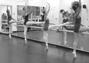Young Women in ballet class working on their form in front of mirrors.